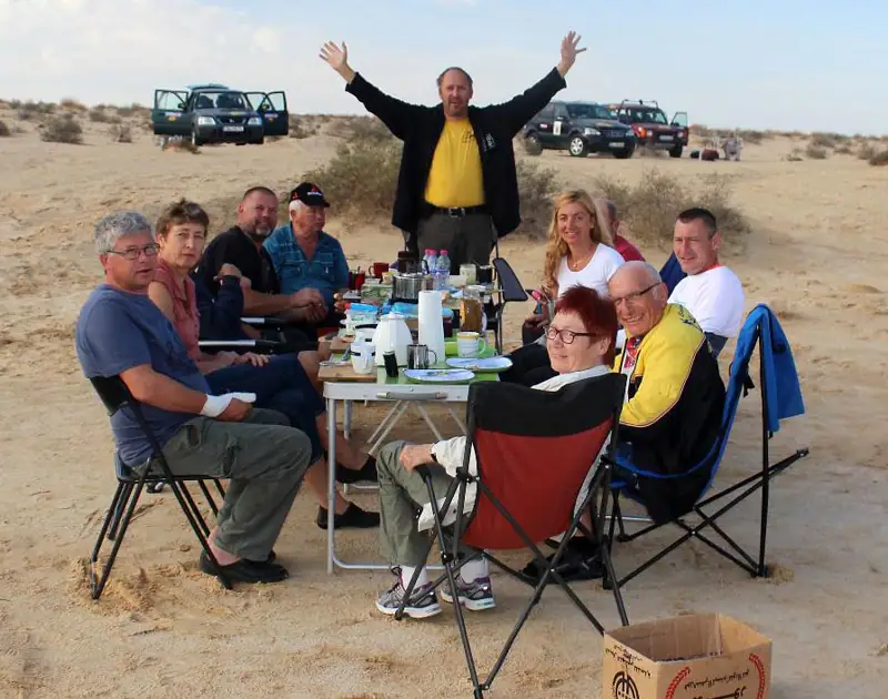 Ein Team von Offroad-Freunden bei der Rast, im Hintergrund die Geländefahrzeuge.